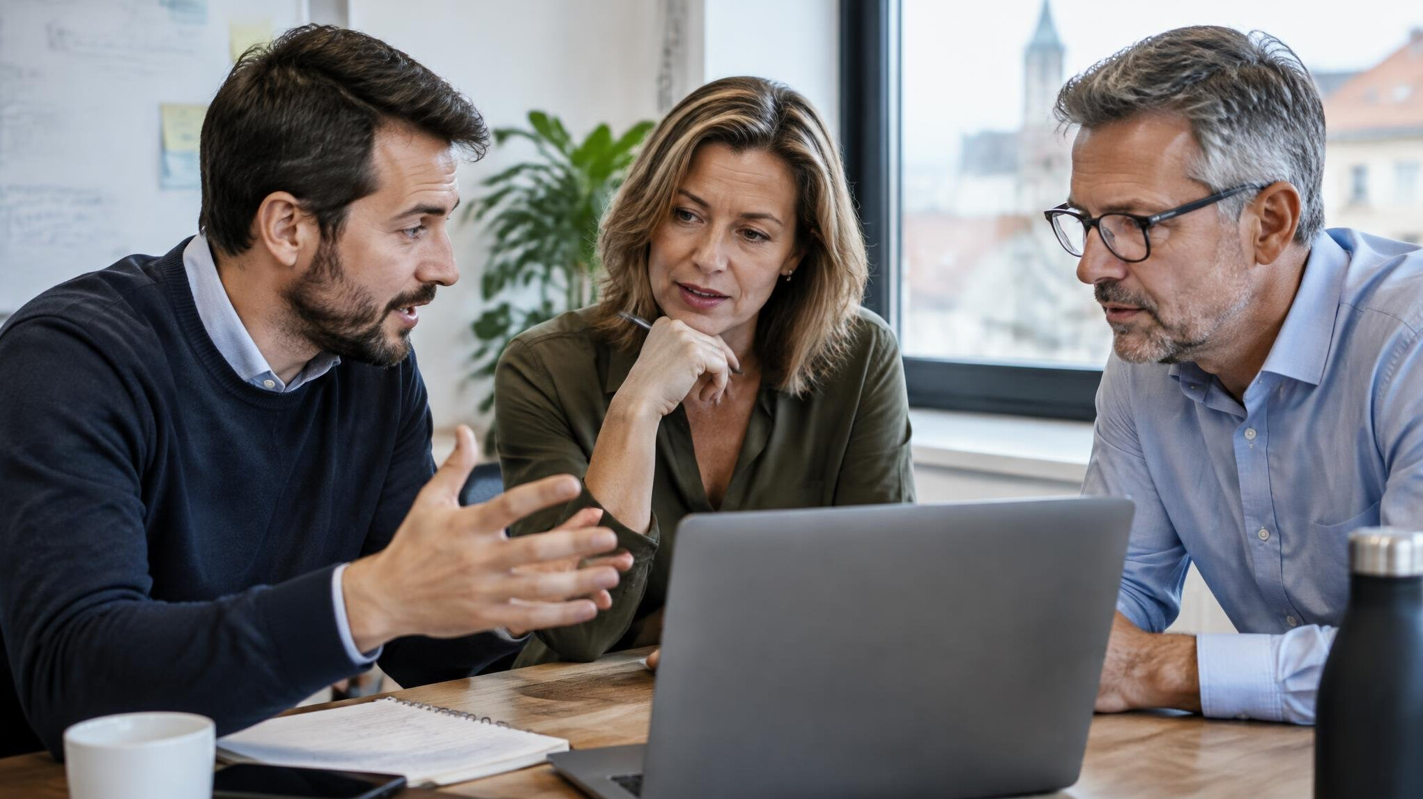 Small group of colleagues in an animated discussion around a laptop